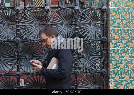 Un piéton passe devant la clôture en fonte de la Casa Vicens conçue par l'architecte moderniste catalan Antoni Gaudí à Barcelone, en Catalogne, en Espagne. Le manoir commandé par le magnat industriel catalan Manuel Vicens comme résidence d'été familiale a été construit entre 1883 et 1885. Les feuilles de la palmier naine méditerranéenne (Chamaerops humilis) également connue sous le nom de palmier éventail européen sont représentées dans la clôture. Banque D'Images