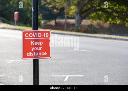 Un panneau lisant Coviid-19 garder votre distance attachée à un lampadaire Banque D'Images