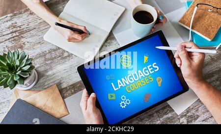 Tablette avec langues pour le texte et les icônes de cours à l'écran. Apprentissage de l'anglais en ligne. Concept d'éducation Banque D'Images