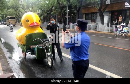 Pékin, Chine. 16 septembre 2020. Un policier chinois documente le retrait d'un canard jaune géant qui orne illégalement l'extérieur d'une entreprise à Pékin le mercredi 16 septembre 2020. La capitale chinoise a récemment sévi contre les entreprises locales qui n'ont pas correctement enregistré les publicités extérieures ou les articles d'affichage non conformes aux normes locales. Photo de Stephen Shaver/UPI crédit: UPI/Alay Live News Banque D'Images