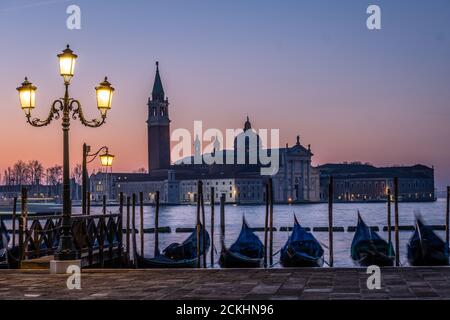 Une lampe sur le front de mer Riva degli Schiavoni avec des gondoles ancrées et la basilique San Giorgio Maggiore en arrière-plan pendant une montée de soleil à Venise, il Banque D'Images