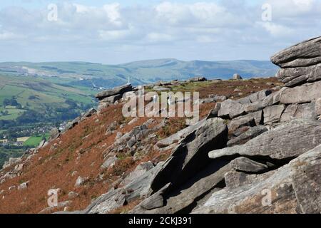 Les grimpeurs avec des sacs à dos marchent le long d'une crête de pierre à terre avec des vues panoramiques sur la campagne de la vallée de l'espoir dans le Peak District, Royaume-Uni Banque D'Images