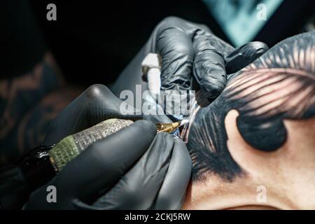 Tatoueur faisant tatouage noir de serpent pour femme Banque D'Images