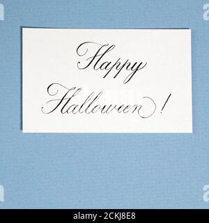 Inscription calligraphique Happy halloween sur papier blanc texturé, sur carte en papier bleue. Décoration Banque D'Images