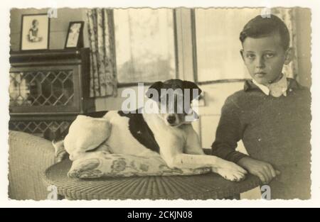 Carte postale du début des années 1900 de jeune garçon portant un pull tricoté avec son chien de terrier Parson Russell,- lieu inconnu, européen, vers les années 1920 années 1930. Banque D'Images