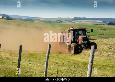 Tracteur travaillant pendant la récolte sur le plateau de Cezallier dans le parc naturel régional des volcans d'Auvergne, Puy de Dome, Auvergne-Rhône-Alpes, France Banque D'Images