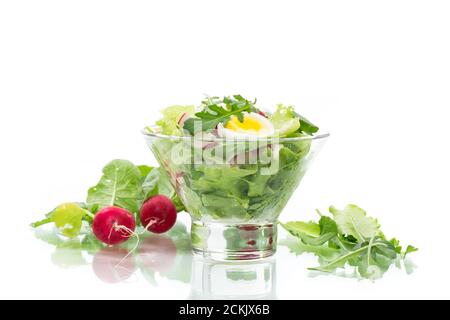 salade de printemps avec roquette, œufs durs, radis frais, feuilles de salade dans un bol en verre Banque D'Images