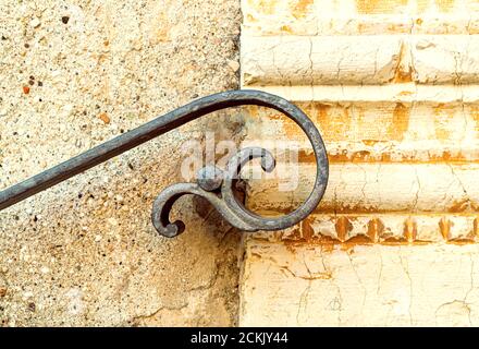 Mur extérieur avec détail de l'ancienne main courante en fer forgé de la forme stylisée d'une personne volante. Sous une partie de la décoration en marbre antique Banque D'Images