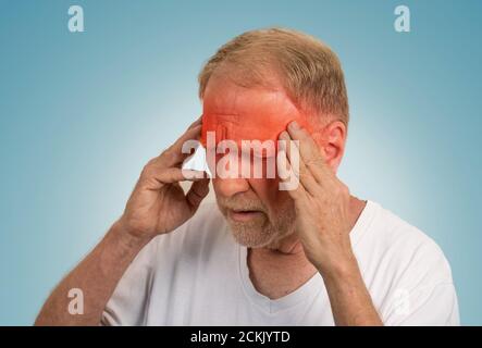Gros plan tête homme senior souffrant de maux de tête mains sur la tête avec des zones enflammées rouges regardant vers le bas isolées sur fond bleu clair. HUMA Banque D'Images