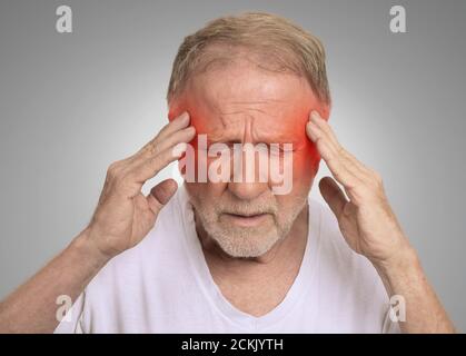 Gros plan tête homme senior souffrant de maux de tête mains sur la tête avec des zones enflammées rouges regardant vers le bas isolées sur fond de mur gris. Humain Banque D'Images