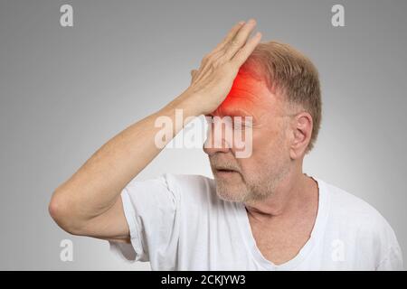 Gros plan tête homme senior souffrant de maux de tête mains sur la tête avec des zones enflammées rouges regardant vers le bas isolées sur fond de mur gris. Humain Banque D'Images