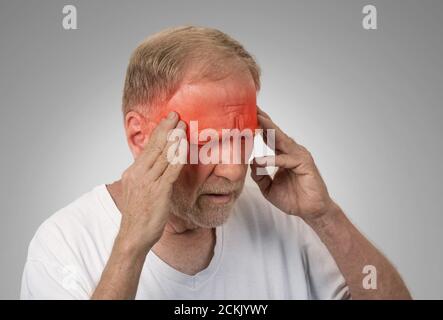 Gros plan tête homme senior souffrant de maux de tête mains sur la tête avec des zones enflammées rouges regardant vers le bas isolées sur fond de mur gris. Humain Banque D'Images