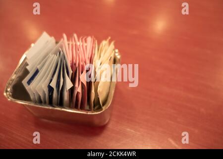 Un récipient de sachets d'édulcorant et de sucre sur une table. Banque D'Images