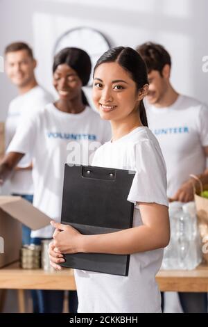 Attention sélective à la tenue de presse-papiers de volontaires asiatiques dans le centre de charité Banque D'Images