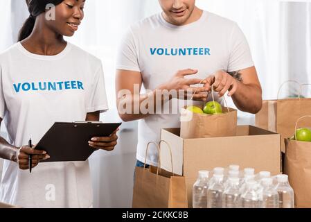 Objectif sélectif du paquet de détention de volontaires avec des pommes proches de l'afrique femme américaine avec presse-papiers Banque D'Images