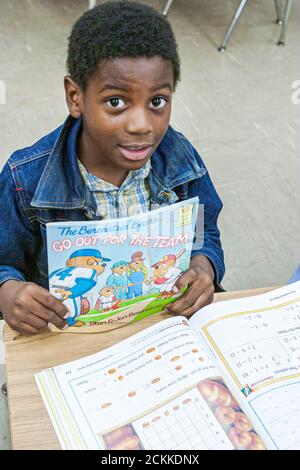 Miami Florida,Frederick Douglass Elementary School,Inside interior primary,communauté de pauvreté de faible revenu,Black Student boy classroom holding book Banque D'Images