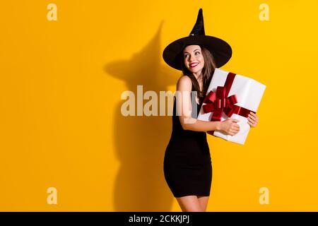 Profil vue de côté portrait d'elle jolie jolie gaie lady wizard tenant entre les mains embrassant la grande boîte-cadeau regardant de côté solde annonce isolée Banque D'Images