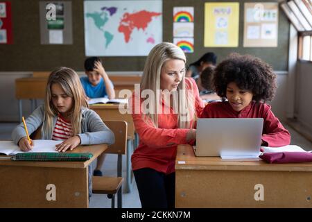 Femme enseignante et garçon utilisant un ordinateur portable en classe à l'école Banque D'Images