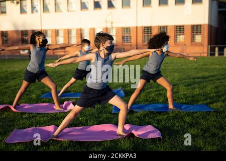 Groupe d'enfants portant des masques de yoga dans le jardin Banque D'Images