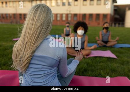 Une enseignante et un groupe d'enfants portant un masque facial s'exécutant yoga dans le jardin Banque D'Images