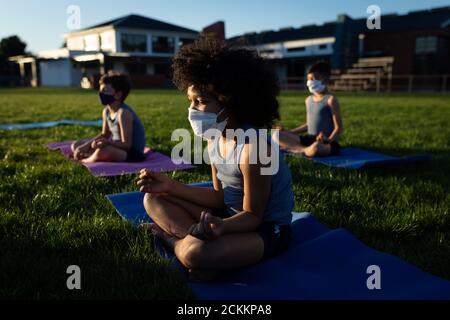 Groupe d'enfants portant des masques de yoga dans le jardin Banque D'Images