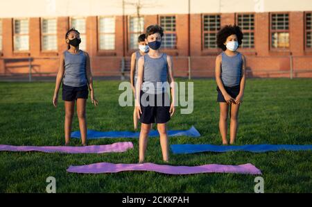 Groupe d'enfants portant des masques de yoga dans le jardin Banque D'Images