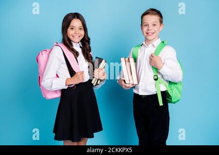 Photo de deux petite fille garçon écoliers frère soeur camarades de classe tenir des livres marcher bibliothèque étude année finition porter sac à dos blanc chemise noire Banque D'Images