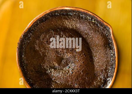 Café naturel avec mousse épaisse, brassé dans une cève de cuivre de la manière classique, sur un fond de bois, photo macro. Banque D'Images