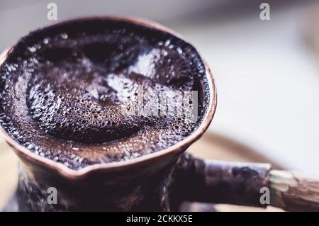 Café naturel avec mousse épaisse, brassé dans une cève de cuivre de la manière classique, sur un fond de bois, photo macro. Banque D'Images