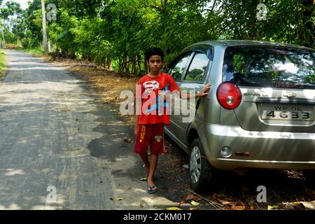 Un garçon indien debout avec sa voiture sur une route de village, en se concentrant de manière sélective Banque D'Images