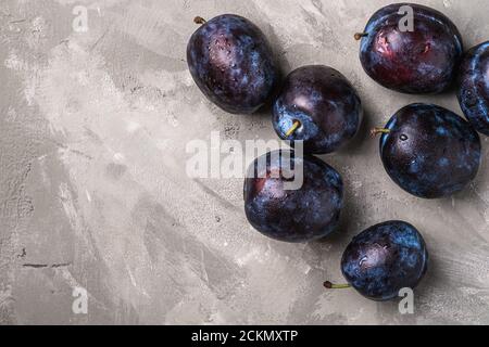 Fruits prune mûrs frais avec gouttes d'eau sur fond de béton de pierre, vue du dessus de l'espace de copie Banque D'Images
