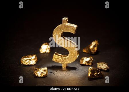 Signe du dollar d'or et nuggets d'or sur fond noir. Banque D'Images