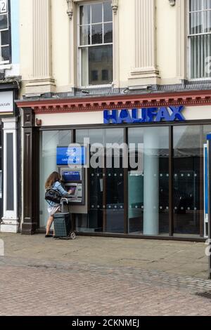 Façade de la Halifax Bank, Market Square, Northampton, Royaume-Uni; femme utilisant un guichet automatique externe. Banque D'Images
