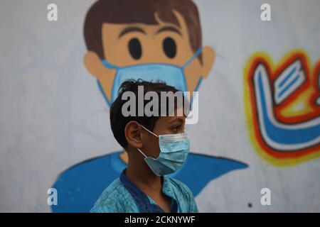 15 septembre 2020, Khanyounis, bande de Gaza, Territoires palestiniens : un garçon palestinien portant un masque facial devant une murale représentant des enfants portant un masque facial peint sur un mur à Khanyounis, dans le sud de la bande de Gaza. (Image crédit : © Ahmad Salem/ZUMA Wire) Banque D'Images