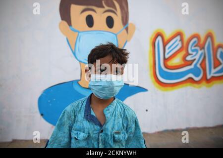 15 septembre 2020, Khanyounis, bande de Gaza, Territoires palestiniens : un garçon palestinien portant un masque facial devant une murale représentant des enfants portant un masque facial peint sur un mur à Khanyounis, dans le sud de la bande de Gaza. (Image crédit : © Ahmad Salem/ZUMA Wire) Banque D'Images