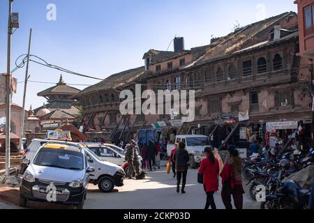 Bhaktapur, Katmandou, Népal - 23 décembre 2019 : des personnes non identifiées se promène dans la rue, des motos et des voitures sont garées sur le côté à côté des boutiques Banque D'Images