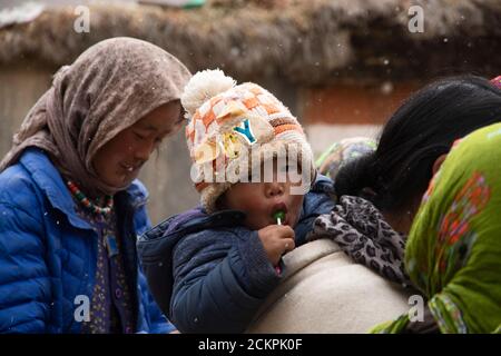 Les gens joyeux de Mud Village, le dernier village de PIN Valley en une journée enneigée se rassemblent dans un marché. Une mère porte son enfant. Banque D'Images