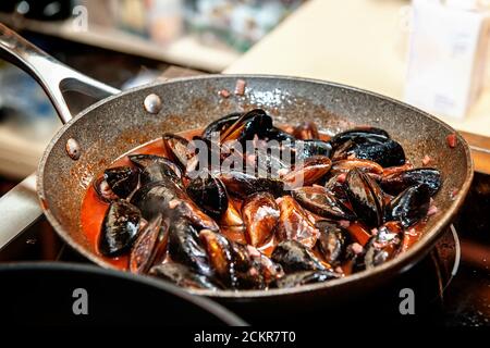 Les moules fraîches sont cuites dans une casserole dans une délicieuse sauce au vin crémeuse. Gros plan de la cuisson des moules dans un restaurant. Mise au point sélective Banque D'Images