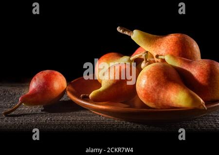 Poires fraîches sur l'assiette. Ancienne table rustique. Récolte de poires. Fruits frais biologiques, concentration sélective. Poires juteuses et savoureuses sur une assiette en bois. Automne nature Banque D'Images