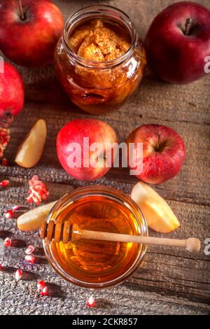 Vacances juives Rosh Hashanah. Pommes, grenade et miel sur la table rustique en bois. Composition de style vintage sur fond de bois rustique. Banque D'Images