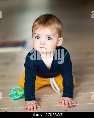 bébé garçon de 6-8 mois sur chenilles avec de grands yeux bleus Banque D'Images