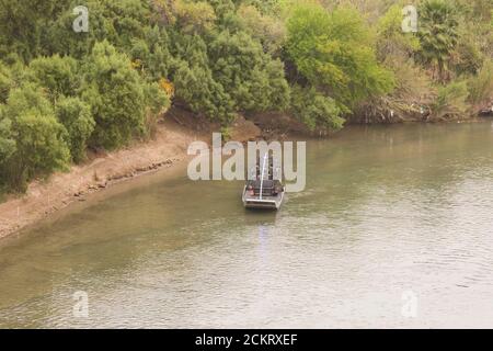 Laredo, TX 20 février 2009 : un hydroglisseur de la patrouille frontalière américaine avec deux agents à bord de patrouilles sur la rivière Rio Grande, en regardant vers l'ouest à travers le centre-ville de Laredo. La frontière des États-Unis est indiquée sur la gauche. ©Bob Daemmrich Banque D'Images