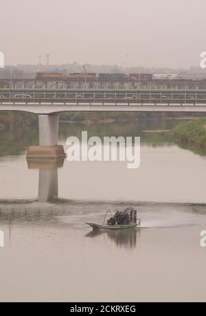 Laredo, TX 20 février 2009 : un hydroglisseur de la patrouille frontalière américaine avec deux agents à bord de patrouilles sur la rivière Rio Grande, en regardant vers l'ouest à travers le centre-ville de Laredo. La frontière des États-Unis est indiquée sur la gauche. ©Bob Daemmrich Banque D'Images