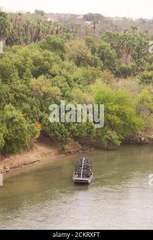 Laredo, TX 20 février 2009 : un hydroglisseur de la patrouille frontalière américaine avec deux agents à bord de patrouilles sur la rivière Rio Grande, en regardant vers l'ouest à travers le centre-ville de Laredo. La frontière des États-Unis est indiquée sur la gauche. ©Bob Daemmrich Banque D'Images