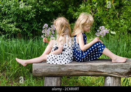 deux belles filles blondes assises sur le banc dans la prairie Banque D'Images