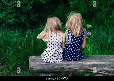 deux filles blondes assises sur le banc avec vue sur le dos Banque D'Images