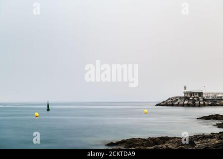Rochers et petit phare lors d'une soirée calme et brumeuse dans le Rias Baixas en Galice, Espagne. Exposition longue. Banque D'Images