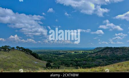 Collines ondoyantes région viticole du Texas central avec des prairies verdoyantes et des forêts avec des nuages blancs boursouflés dans un ciel bleu le jour chaud d'été. Banque D'Images