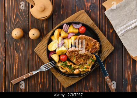 Assiette avec filet de porc frit, quartiers de pommes de terre, champignons et tomates Banque D'Images