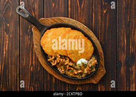 Poêle en fonte avec chanterelles frites, champignons au miel et crêpes aux pommes de terre à la sauce crémeuse Banque D'Images